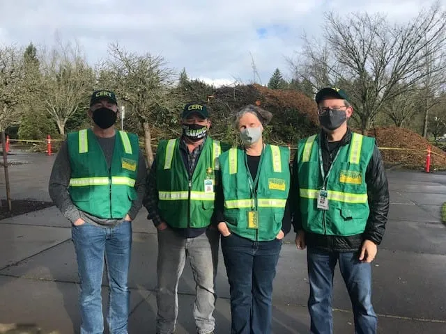 Four people in green vests and face masks