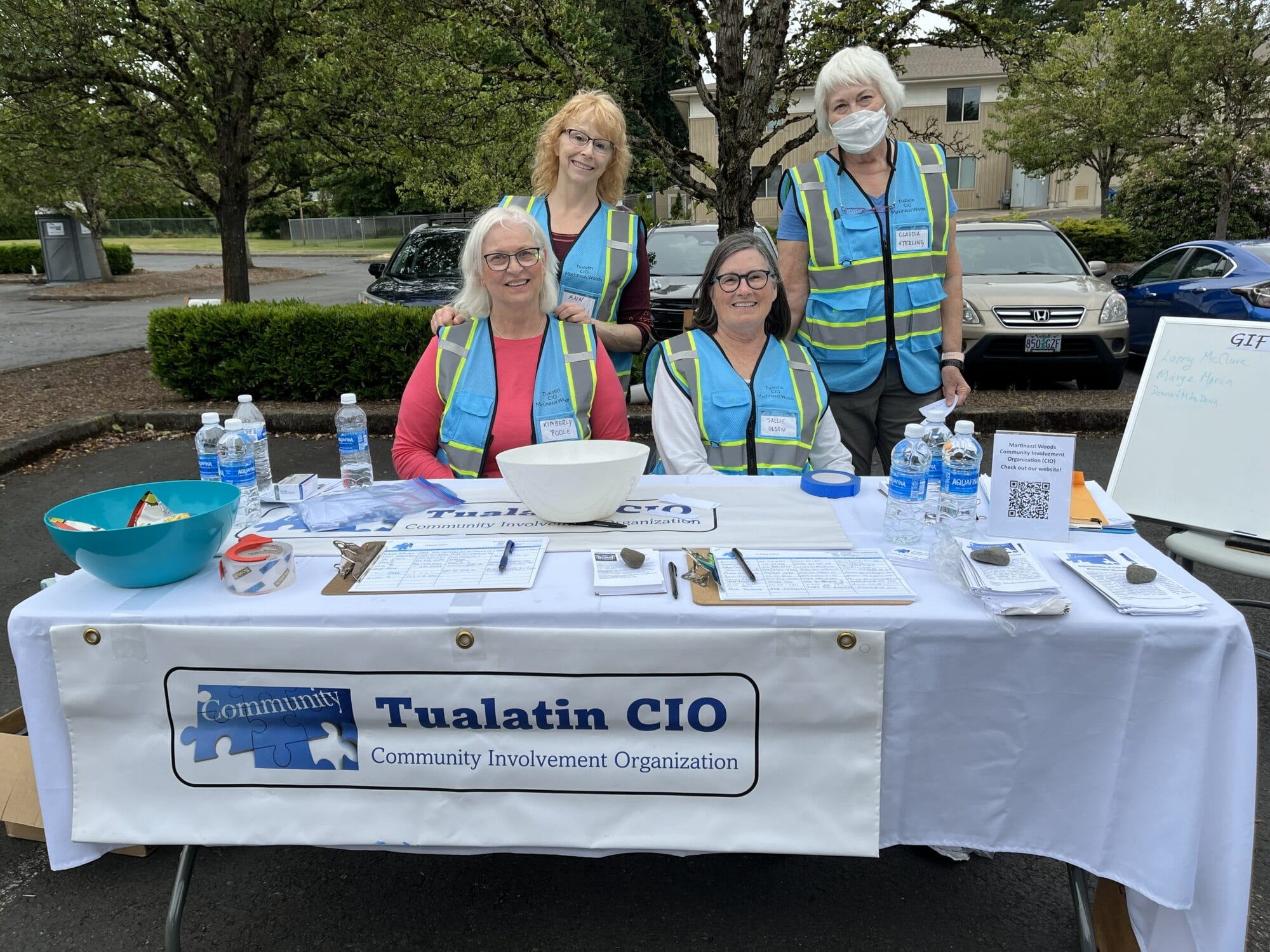 Four women in blue vests sitting at a table
