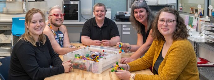 Tualatin staff members sit around a table in the Makerspace lab with a box of multiple colors of thread