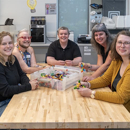 Tualatin staff members sit around a table in the Makerspace lab with a box of multiple colors of thread